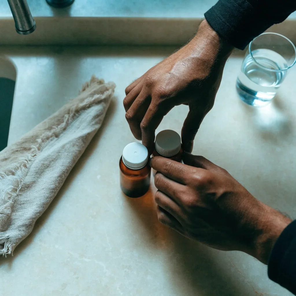 Manos ordenando dos frascos de cápsulas naturales junto a una guía impresa en una mesa de cocina