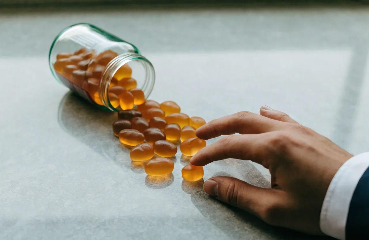 Gomitas con omega-3 saliendo de un frasco sobre encimera de piedra clara